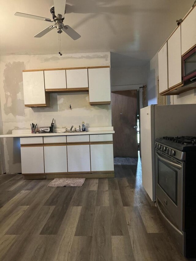 kitchen with white cabinets, stainless steel gas stove, dark hardwood / wood-style floors, and sink