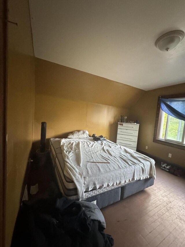 bedroom with vaulted ceiling and hardwood / wood-style flooring