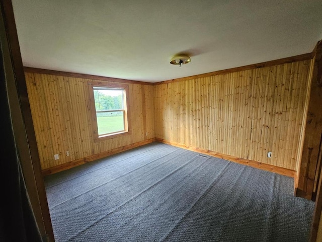 carpeted spare room with wood walls