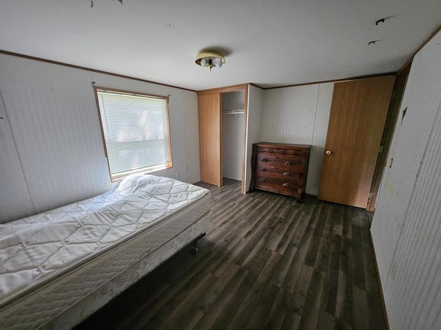 bedroom with dark wood-type flooring, a closet, ornamental molding, and wooden walls