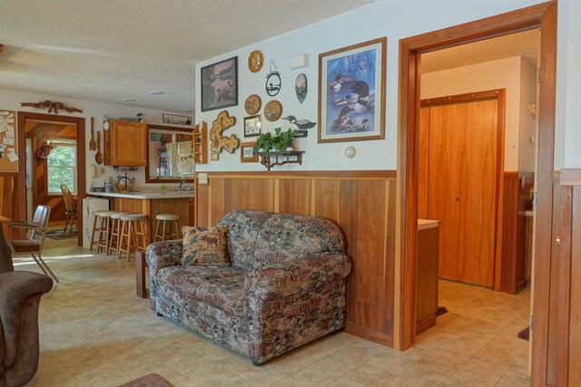 living room featuring a textured ceiling and wood walls