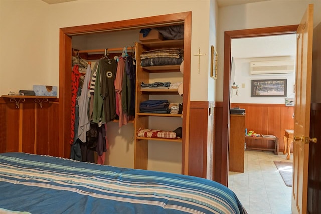 bedroom featuring a wall unit AC, a closet, and wood walls