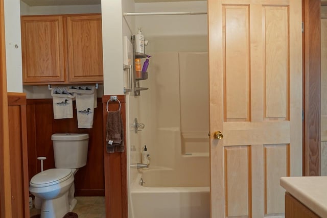 bathroom with toilet, wood walls, and washtub / shower combination