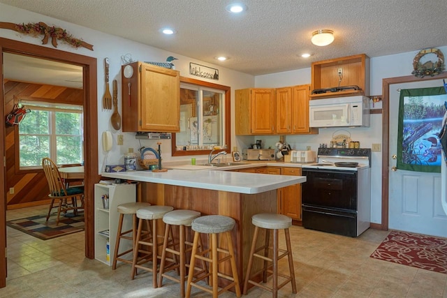 kitchen with a textured ceiling, a breakfast bar area, range with electric stovetop, and wood walls