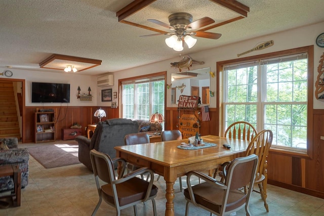 dining area with plenty of natural light, a textured ceiling, a wall unit AC, and wooden walls