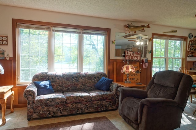 living room with light tile patterned flooring, wood walls, and a textured ceiling