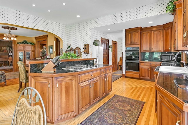 kitchen featuring backsplash, white appliances, sink, light hardwood / wood-style flooring, and a center island