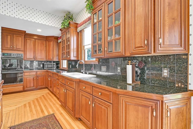 kitchen featuring light wood-type flooring, decorative backsplash, double oven, and sink