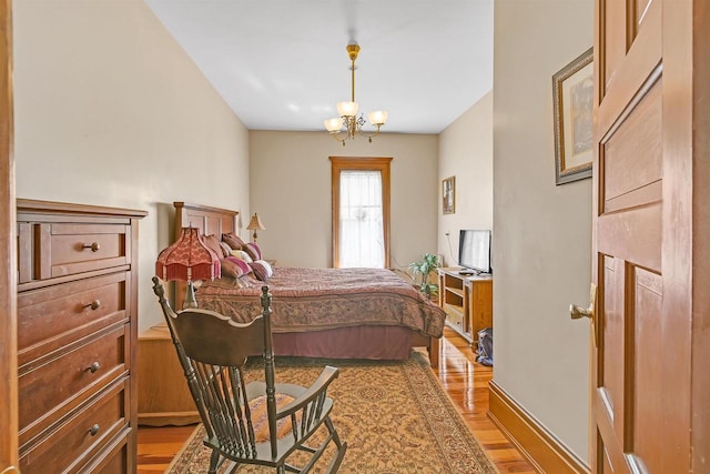 bedroom with light hardwood / wood-style floors and a notable chandelier