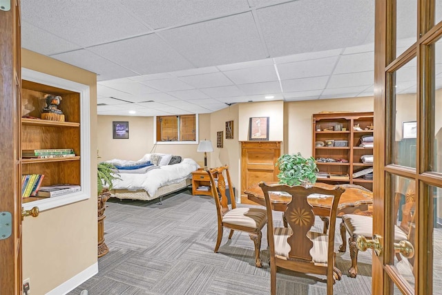 dining area with a paneled ceiling, carpet, and built in features