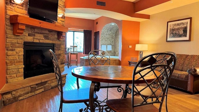 dining room with light hardwood / wood-style flooring and a stone fireplace