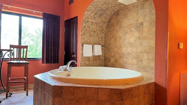 bathroom with tile patterned flooring and a relaxing tiled tub