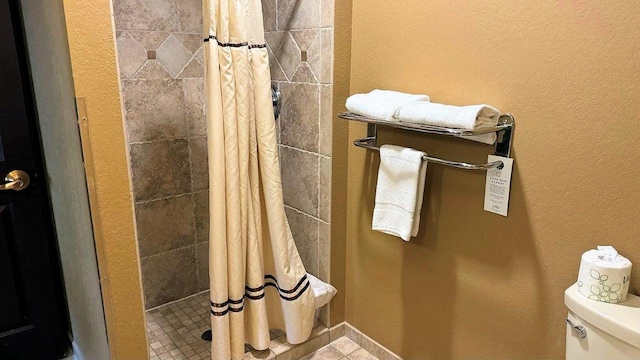 bathroom featuring toilet and curtained shower