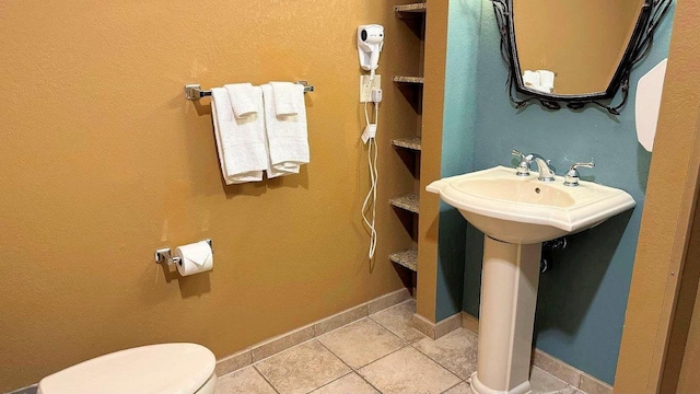 bathroom with toilet, tile patterned flooring, and sink