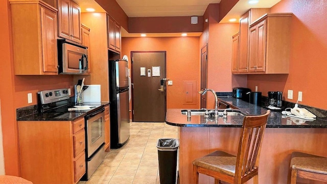 kitchen with a breakfast bar area, appliances with stainless steel finishes, kitchen peninsula, and sink