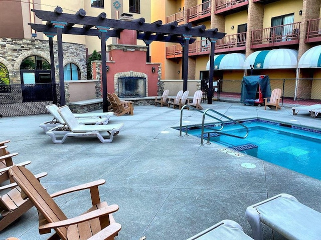 view of swimming pool featuring a patio area and an outdoor stone fireplace