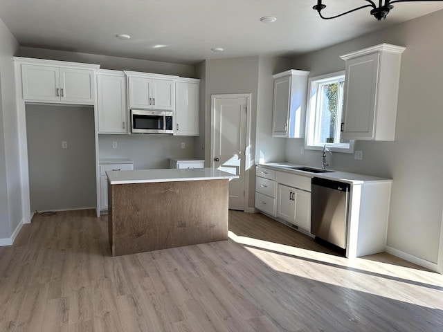 kitchen featuring white cabinets, appliances with stainless steel finishes, a center island, and sink