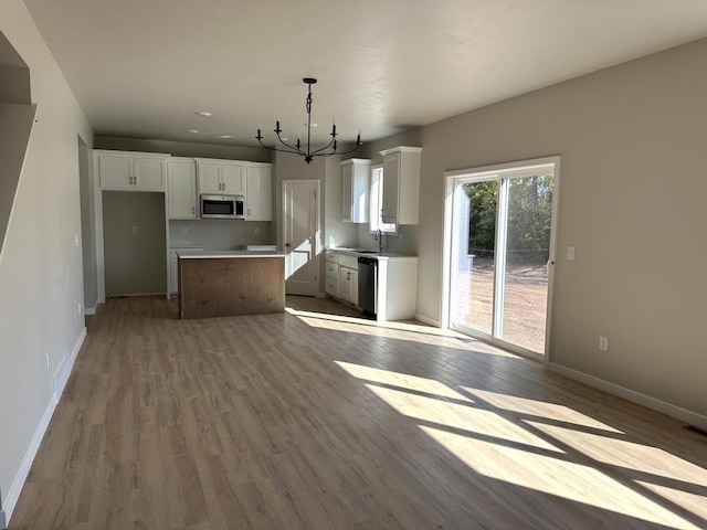 kitchen featuring light hardwood / wood-style floors, an inviting chandelier, hanging light fixtures, appliances with stainless steel finishes, and white cabinets