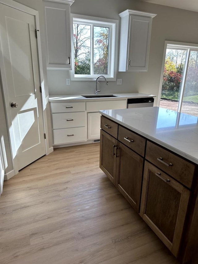 kitchen featuring light hardwood / wood-style floors, sink, white cabinetry, and stainless steel dishwasher