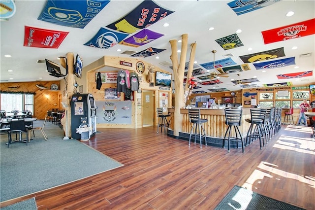 interior space featuring hardwood / wood-style floors, wood walls, and bar area