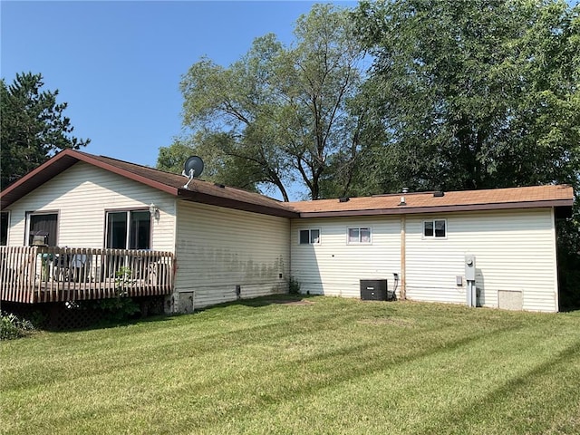 back of property with a wooden deck, central air condition unit, and a yard