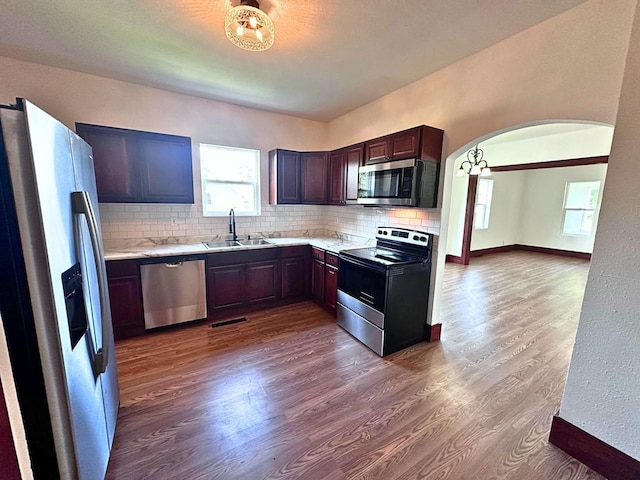 kitchen with hardwood / wood-style floors, dark brown cabinetry, appliances with stainless steel finishes, tasteful backsplash, and sink