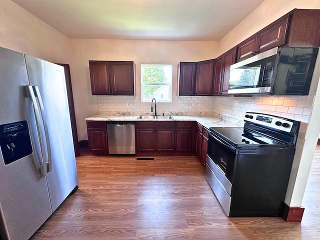 kitchen with tasteful backsplash, sink, stainless steel appliances, and hardwood / wood-style flooring