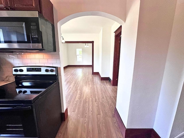 kitchen featuring light wood-type flooring, stainless steel appliances, and tasteful backsplash