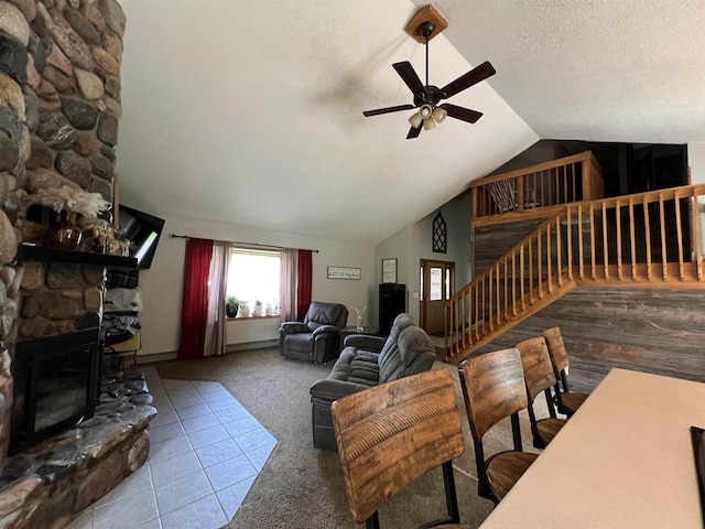 living room featuring a stone fireplace, lofted ceiling, carpet floors, ceiling fan, and a textured ceiling