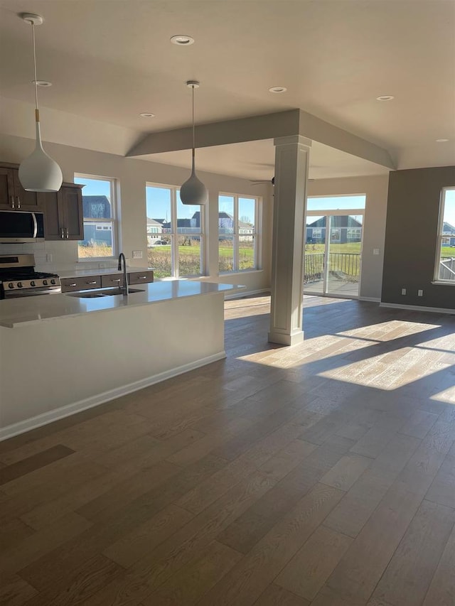 kitchen featuring dark hardwood / wood-style floors, pendant lighting, decorative backsplash, appliances with stainless steel finishes, and dark brown cabinets