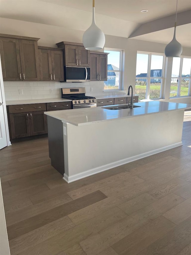 kitchen with gas range, decorative light fixtures, backsplash, and sink