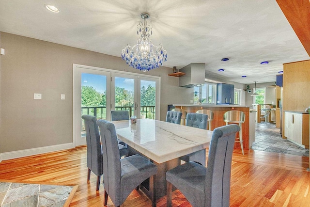 dining room featuring light wood-type flooring, an inviting chandelier, and french doors