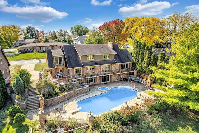 rear view of property featuring a pool with hot tub and a patio area