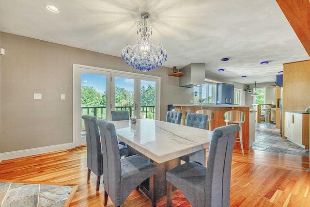 dining space featuring an inviting chandelier, french doors, and light wood-type flooring