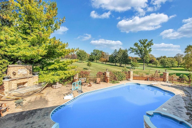 view of swimming pool featuring a patio area, an outdoor stone fireplace, and a yard