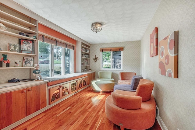 sitting room featuring light wood-type flooring and built in features