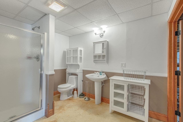 bathroom featuring a drop ceiling, toilet, and a shower with door