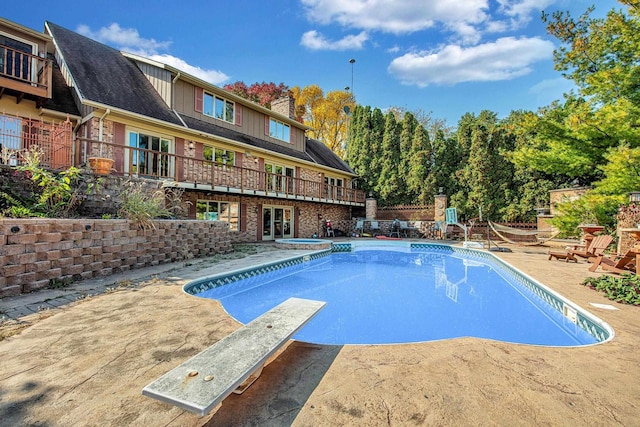 view of swimming pool with a diving board and a patio