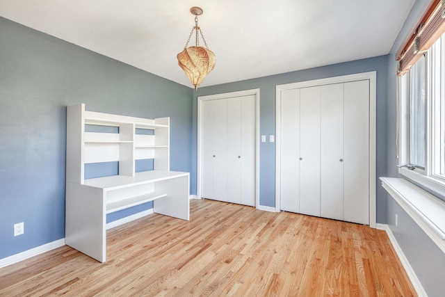 unfurnished bedroom with light wood-type flooring and two closets