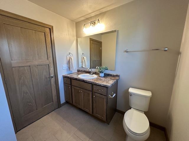 bathroom with toilet, vanity, and tile patterned flooring