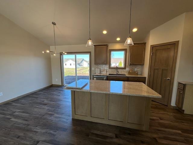 kitchen featuring decorative backsplash, dark hardwood / wood-style floors, a center island, decorative light fixtures, and sink