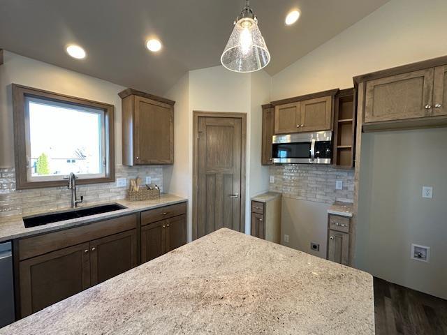 kitchen featuring sink, hanging light fixtures, lofted ceiling, and tasteful backsplash