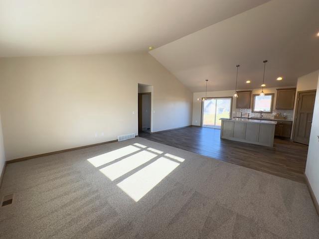 unfurnished living room featuring dark carpet and vaulted ceiling