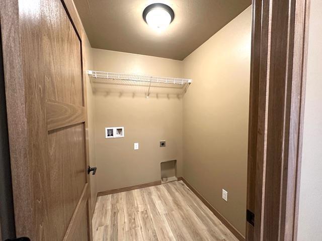 clothes washing area featuring light hardwood / wood-style floors, hookup for a washing machine, and electric dryer hookup