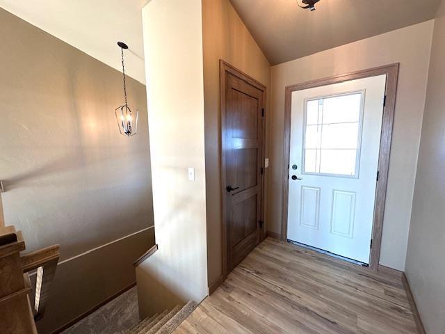 doorway to outside featuring light hardwood / wood-style floors, a notable chandelier, and vaulted ceiling