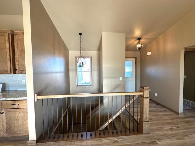 interior space featuring lofted ceiling, wood finished floors, an upstairs landing, and baseboards