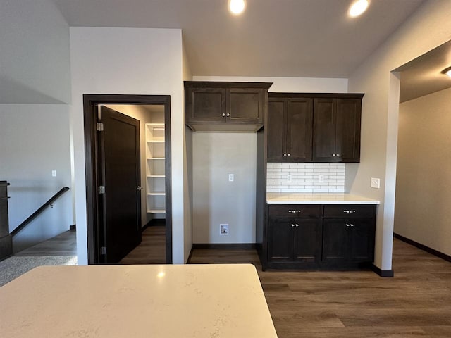 kitchen featuring backsplash, dark wood-type flooring, and dark brown cabinets