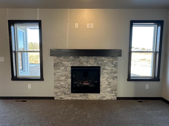 unfurnished living room featuring carpet flooring and a stone fireplace