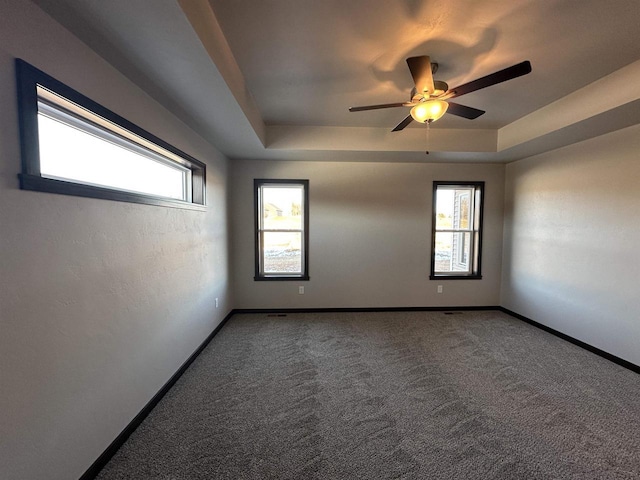 unfurnished room with ceiling fan, carpet, and a tray ceiling