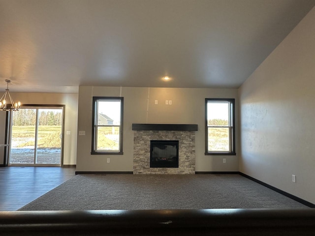 unfurnished living room featuring vaulted ceiling, a notable chandelier, and a fireplace